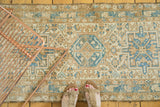 Distressed geometric Karaja runner with central medallion in ivory, sky blue, and brown.