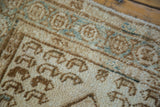 Distressed hand-knotted pile texture with bronze and ivory geometric motifs and aqua accents.