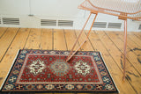 Cherry red and charcoal geometric medallions on a vintage hand knotted Indian square mat.