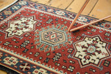 Hand-knotted central geometric medallion with cherry red field stylizations.