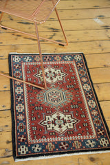 Detailed corner of vintage Indian rug with geometric patterns, cherry red, charcoal, and blue.