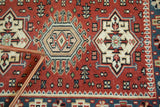 Intricate geometric medallion and a detailed blue border on cherry red vintage Indian rug.