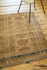 Vintage Afghan rug with linear medallions, barber pole border, and dark navy aqua.
