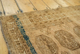 Distressed vintage Afghan rug, showing elephant footprint medallions and dark navy aqua stripe.
