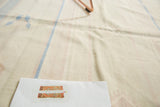 Woven texture of a vintage Dhurrie rug with light stripes and visible staining.
