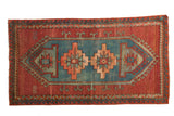 Vintage Caucasian rug featuring an aqua blue geometric medallion, brick red field, and wave motif.