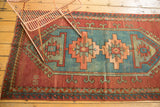 Geometric vintage Caucasian rug featuring an aqua blue medallion and brick red field, wave motif.