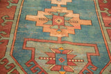 Geometric wave motifs of a vintage Caucasian rug in aqua, brick red, and blush tones.