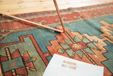 Hand-knotted vintage Caucasian rug detail with geometric patterns in brick red and aqua blue.