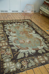 Geometric border and rococo-like scrolls on vintage hand woven carpet in earthen tones.