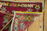 Hand-knotted Oushak rug corner revealing cherry red floral pile and tight woven foundation.