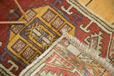 Vintage Oushak rug folded, exposing hand-knotted back, fringe, geometric red and yellow pattern.