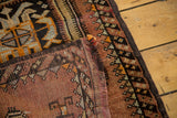Detail of vintage Oushak rug showing irregular weave, barber pole border, and tattered edge.
