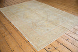 Secured corner of an antique Turkish Kaisary rug with muted floral border and distressed pile.