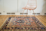Vintage Heriz square rug with navy oversize medallion, brick red field, geometric border.