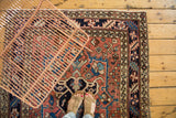 Vintage Heriz rug with brick red field, navy blue stylized florals, and geometric pattern border.