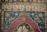 Distressed Oushak carpet texture with black cherry red medallion and deep indigo floral abrash.