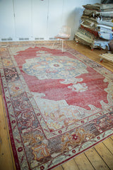 Distressed Oushak rug border showing crimson red, ivory, saffron, and charcoal patterns.