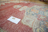 Decorative distressed pile on a vintage Oushak rug, showcasing crimson, saffron, and ivory tones.
