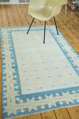 Vintage Dhurrie rug corner with geometric star border in denim blue, sea foam green, pale yellow.