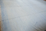Hand woven Dhurrie carpet showing subtle pale powder blue and ivory minimalist texture and fringe.