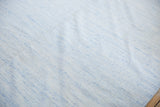 Minimalist Dhurrie carpet texture, showing subtle pale powder blue and ivory yarns.