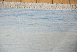 Dhurrie carpet's hand woven texture, subtle pale powder blue, denim, ivory striations, and fringe.