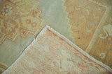 Folded corner of vintage Oushak runner reveals hand-knotted foundation and pastel stepped pattern.