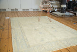 Corner of vintage Oushak rug, ivory field, pale blue scattered motifs and carved pile.