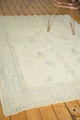 Pale blue scattered motifs and ivory partially carved pile on a Vintage Oushak rug.