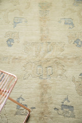 Partially carved pile of vintage Oushak rug: scattered ivory, beige, and pale blue motifs.