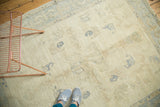 Vintage Oushak rug displaying scattered ivory and pale blue motifs, with light staining.