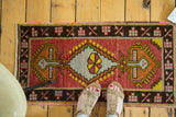 Geometric stepped medallion with pinwheel design in brick red, silver, and saffron yellow.