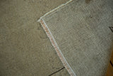 Folded vintage Distressed Oushak rug revealing its low pile, hand-knotted foundation, and fringe.