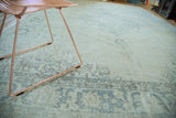 Distressed vintage Oushak carpet, showing faded pale blue, grey, and ivory pattern motifs.