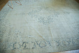 Distressed vintage Oushak rug corner with faded grey-blue geometric border.