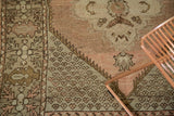 Vintage Oushak rug detail, geometric border meeting allover patterns in peach and blush tones.