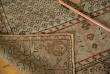 Folded vintage Oushak rug showing soft peach pile and tight woven geometric back with fringe.