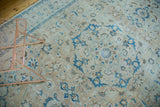 Intricate blue palmettes and scrolling tendrils on a distressed sand Tabriz carpet.