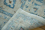 Folded corner of vintage Tabriz carpet, showcasing hand-knotted fringe and aged mallard green patterns.