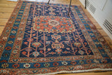 Distressed dark indigo and madder red geometric borders of a vintage Heriz rug, with fringe.