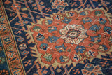 Textured vintage Persian Heriz rug detail showing bold indigo and madder red geometric motifs.