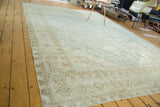 Distressed Oushak rug corner with faded mint green field and intricate beige geometric patterns.