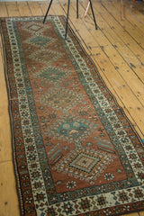 Vintage Heriz runner showing copper, teal geometric diamonds and a star motif border.