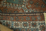 Folded Heriz runner's geometric border featuring star and floral motifs in madder red, teal, ivory.