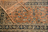 Antique Heriz runner's geometric floral field and wave border in peach, navy, sky blue.