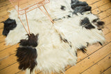 Shaggy ivory and jet black angora pelt, showcasing soft cowhide-like texture.