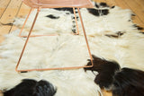 Soft, shaggy ivory and black angora pelt rug with cowhide-like pattern.
