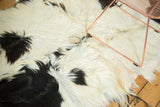 Luxurious angora skin rug close-up with soft ivory, jet black, and bronze cow-like pattern.