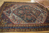 Distressed antique Qashqai rug border with geometric and stylized floral motifs in red, blue, and gold.